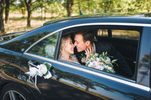 A Modern Bride And Groom In A Lace Dress In A Car Window. Beautiful And Smiling Newlyweds.