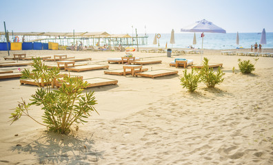 Fototapete - Sandy beach on blue sea background. Umbrellas and deck chairs on shore of sea. Summer day on beach rest. Vacation concept. View on sea beach in sunny clear day in Turkey Konakli.