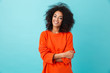 Colorful portrait of amazing woman in red shirt with afro hairstyle looking on camera with smile, isolated over blue background