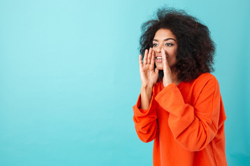 Sticker - Cute american woman in colorful shirt with shaggy hair shouting or calling holding hands at mouth, isolated over blue background