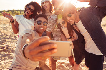 Wall Mural - Excited young friends on the beach make selfie