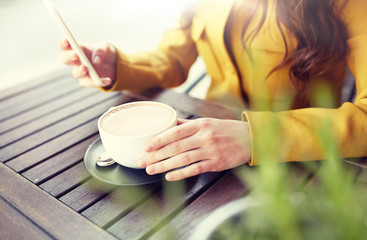 Canvas Print - communication, technology, leisure and people concept - close up of young woman or teenage girl texting on smartphone and drinking cocoa at city street cafe terrace