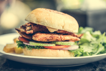 Wall Mural - street food fishburger with fish cutlet and vegetables on white plate.