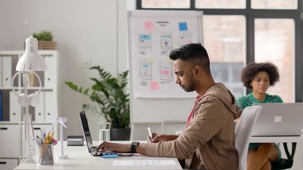 Wall Mural - business and creative people concept - young indian man with laptop computer working at office