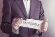 © Iana Alter - motivation concept. Businessman tearing sign saying - Impossible - conceptual of successfully overcoming problems and challenges and positive attitude.