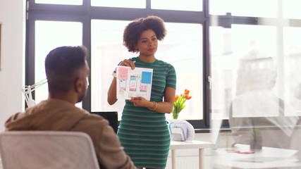 business, technology and software development concept - woman showing user interface mockup to creative team at office
