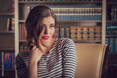 Poster Young caucasian woman dressed in mid century casual fashion poses in a library