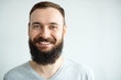Portrait of a beautiful real hipster man teeth smile with a full face of a beard and mustache on a light  background in a barber shop