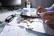 © Andrey Popov - Businessperson Calculating Receipt With Calculator