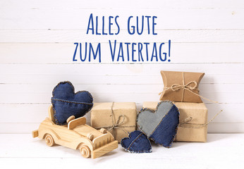 Wall Mural - Father's Day card with wooden toy car, gift boxes and denim hearts.  German text 