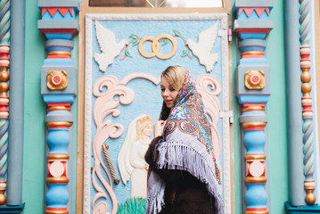 A young beautiful girl in a mink coat and a Russian folk scarf walks around the Izmailovo Kremlin. Moscow, Russia.