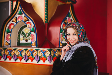 A young beautiful girl in a mink coat and a Russian folk scarf walks around the Izmailovo Kremlin. Moscow, Russia.