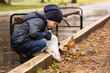 © viclin - Little girl in trench coat feeding squirrel in park.