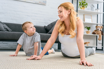 Happy mother and son practicing yoga in modern living room