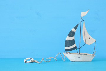 nautical concept with white decorative sail boat over blue wooden table and background.