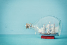 Nautical Concept Image With Sail Boat In The Bottle Over Blue Wooden Table And Background. Selective Focus.