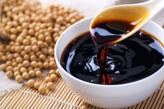 Fototapete - Pouring soy sauce into a white bowl