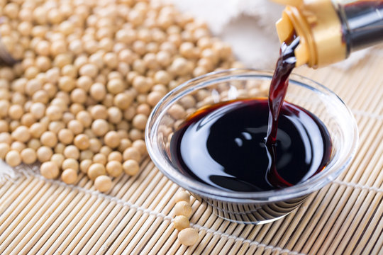 Fototapete - Close up of pouring soy sauce in glass bowl
