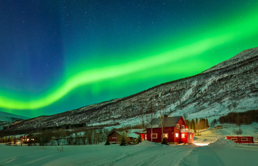 green northern lights over rural county of northern norway