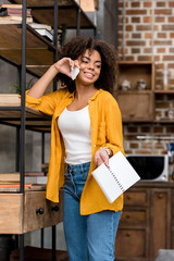 Wall Mural - beautiful young woman with book talking by phone at home