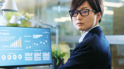 Wall Mural - In the Stock Market Firm Office Broker Works with Statistical Information. Dramatically Turns His Head and Looks into the Camera. Stylish Concrete and Glass Office Shared with Beuatiful Coworker.