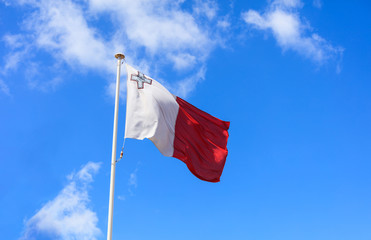 Sticker - Malta flag. Malta flag on a pole waving on blue sky background