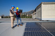 © franco lucato - young engineer girl and an elderly skilled worker fitting a photovoltaic plant