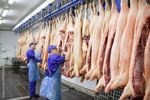 Cuadros en Lienzo Butcher cutting pork at the meat manufacturing.