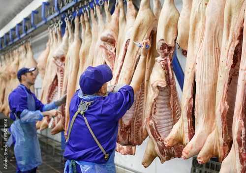Fotografía Butcher cutting pork at the meat manufacturing.
