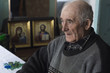 © Oleksandr - Portrait of an elderly man. Grandfather sits in his room in the background of the icons.