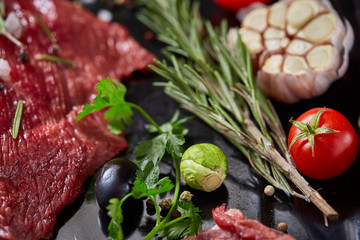 Wall Mural - Flat lay of raw beefsteak with vegetables, herbs and spicies on metal tray, close-up, selective focus