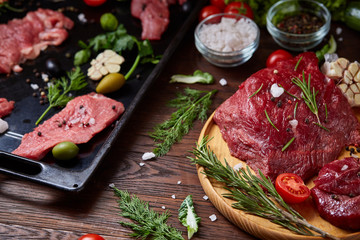 Wall Mural - Flat lay of raw beefsteak with vegetables, herbs and spicies on metal tray, close-up, selective focus