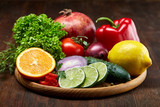 Fototapeta Kuchnia - Still life of fresh organic vegetables on wooden plate over wooden background, selective focus, close-up