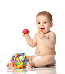 Wall Mural - Infant child baby boy toddler sitting in diaper playing with balls and plastic toys isolated 