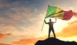Mali flag being waved by a man celebrating success at the top of a mountain. 3D Rendering