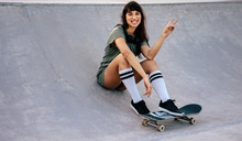 Female Skateboarder With Peace Sign At Skate Park
