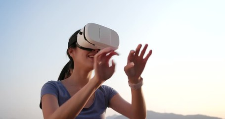 Wall Mural - Woman playing with VR device over the sky background