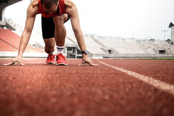 Sport. Runner on the start line. Sprinter starting on the running track. Athletic man running on the stadium track