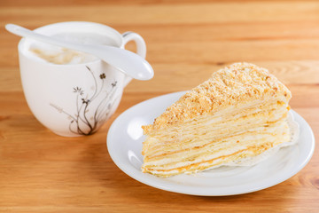 Canvas Print - Slice of sweet classic layered cake Napoleon and cup of cappuccino on the wooden table