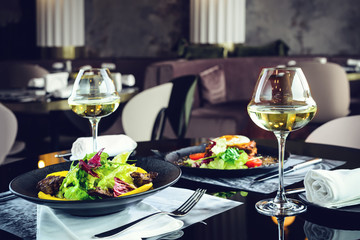 Sticker - Romantic dinner at a restaurant. Appetizing dishes with meat and lettuce leaves and glasses with wine