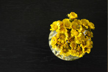 Bouquet Of Yellow Flowers In A Vase On A Black Wooden Background, A Beautiful Spring Composition, A Top View