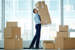 © pressmaster - Young businessman carrying huge stack of big boxes with office supplies during relocation to modern business center