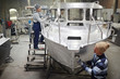 Modern shipbuilding engineers working over new boat in production factory