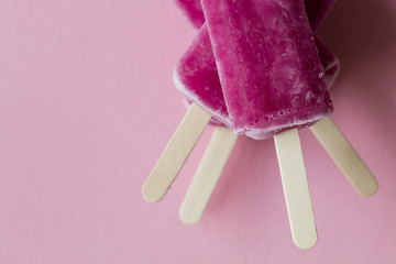 Raspberry flavour summertime ice lollies on a pink background