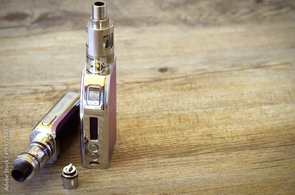Two e-cigarettes with atomizer over a rustic wooden table. Vaping  background. Concet image for vape shop. Old film photography era effect.  Stock Photo | Adobe Stock