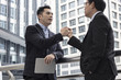 © khwanchai - Successful negotiating business concept, Businessmen shaking hands after finishing meeting or setting  goals and planning way to success in front of building