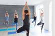© uv_group - Yoga men instructor teaches group of people, fitness, sport and healthy lifestyle concept. Young women with personal trainer doing yoga exercises on mat in gym studio