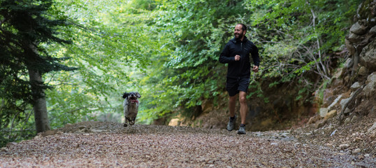 man running with his dog around the forest