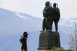 pomnik w szkocji upamiętniający żołnierzy poległych w walce oraz grający na kobzie szkot i góry w tle