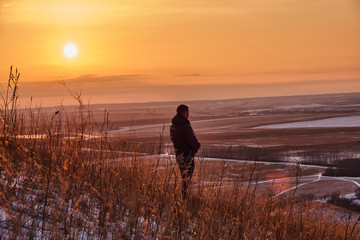 man on the mountain at sunset.The man on the mountain at sunset in the late autumn looks into the distance